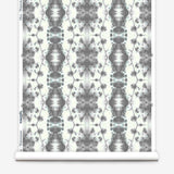 Partially unrolled wallpaper yardage in a painterly gometric stripe in gray and blue on a cream field.