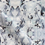 Detail of fabric in a watercolor paint blotch print in blue, gray and purple on a white field.