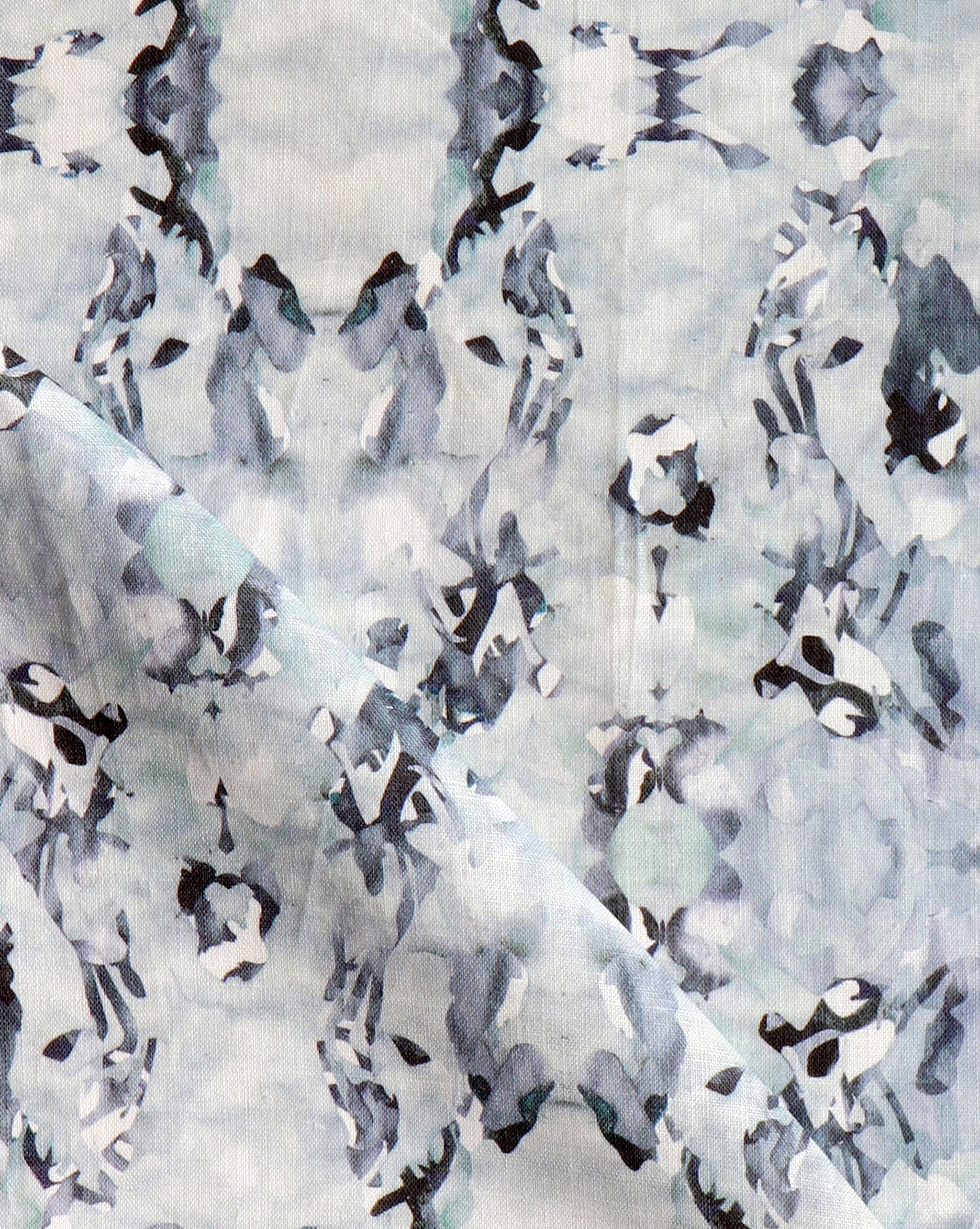 Detail of fabric in a watercolor paint blotch print in blue, gray and purple on a white field.