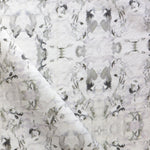Detail of fabric in a watercolor paint blotch print in purple and gray on a white field.