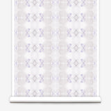 Partially unrolled wallpaper yardage in a striped ink blot print in shades of tan and purple on a cream field.