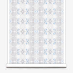 Partially unrolled wallpaper yardage in a striped ink blot print in shades of gray and blue on a cream field.