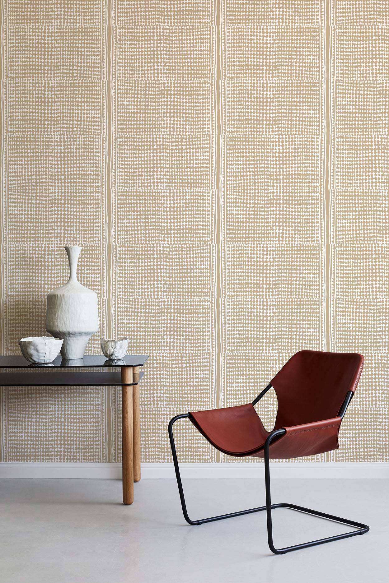 Modern brown chair and small table against a beige wallpapered wall.
