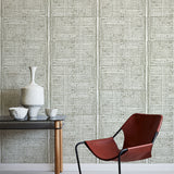 Modern brown chair and small table against a green geometric wallpaper