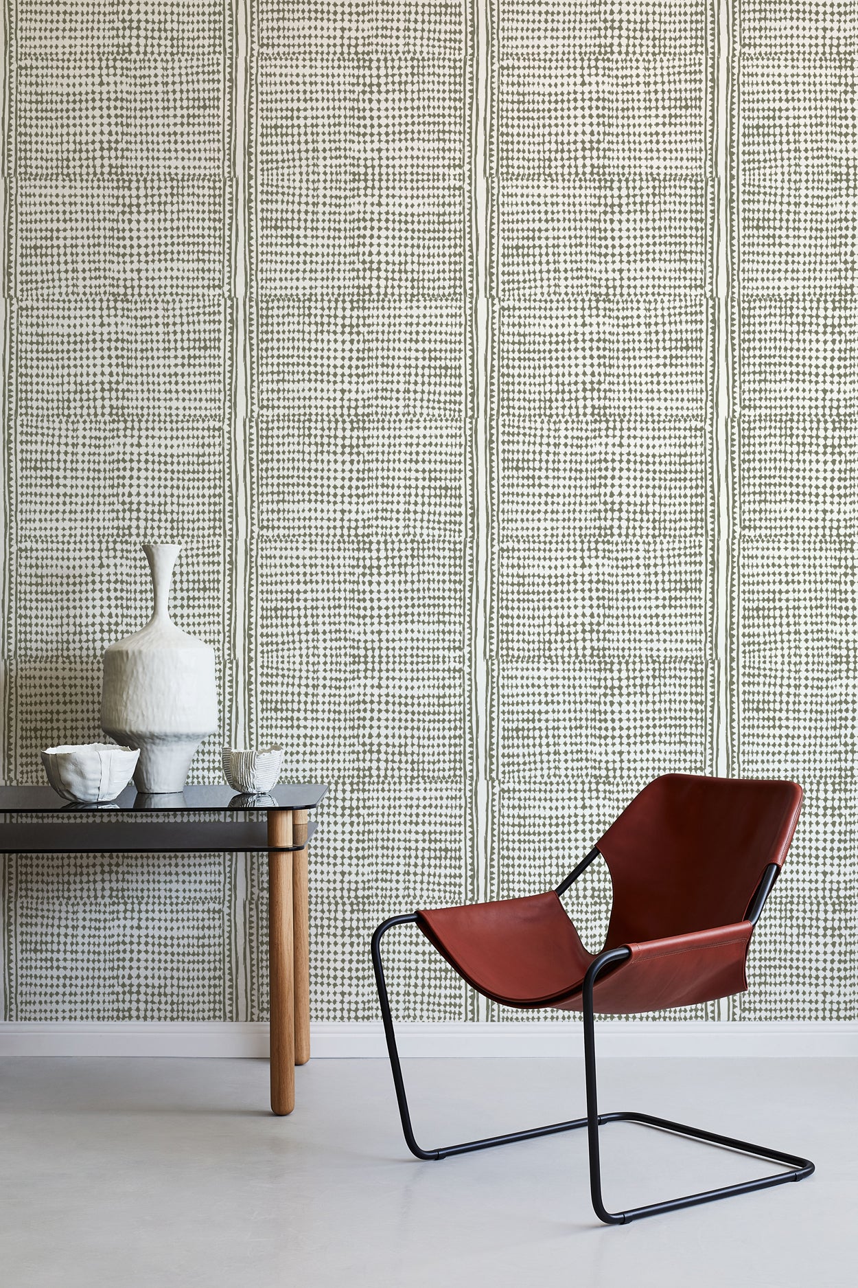 Modern brown chair and small table against a green geometric wallpaper