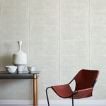 Brown chair and small table against a grey geometric wallpaper