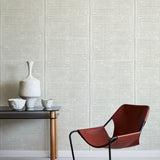 Brown chair and small table against a grey geometric wallpaper