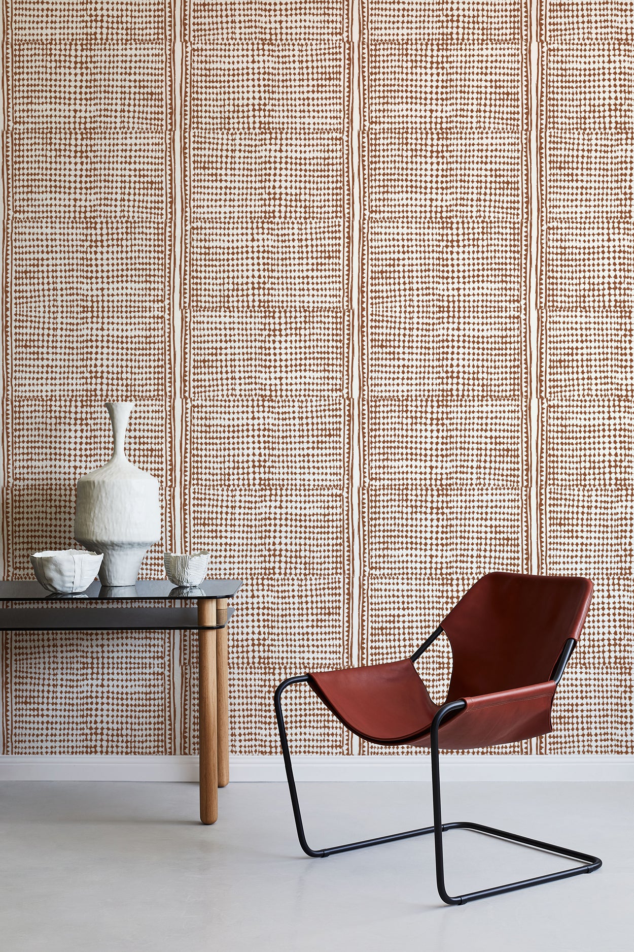 Modern brown chair with black frame against a brown geometric wallpaper