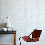 Modern interior with a brown chair, small table, and decorative items against a blue geometric wallpaper
