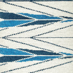 Handknotted rug sample in a modern herringbone design in shades of blue ona. white field. 