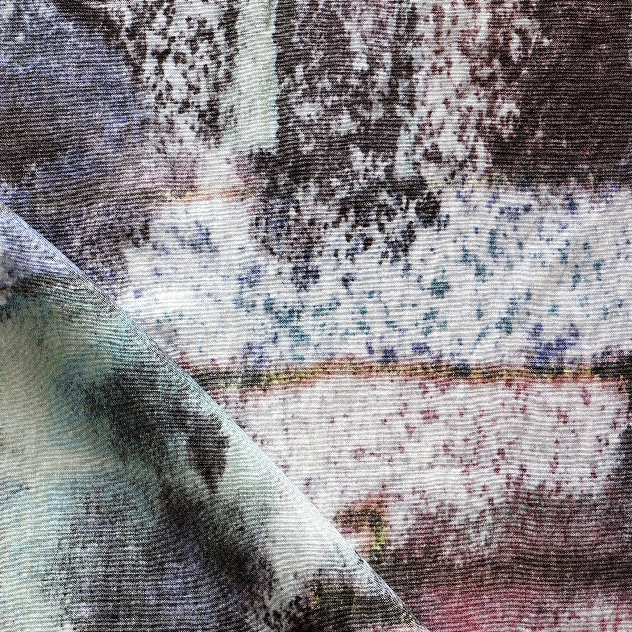 Detail of fabric in a minimal splatter print in shades of green, brown and pink on a cream field.