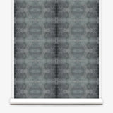 Partially unrolled wallpaper yardage in a repeating ink blot print in shades of gray.