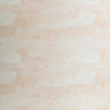A flower lays in front of a wall papered in an abstract textural pattern in shades of white and pink.