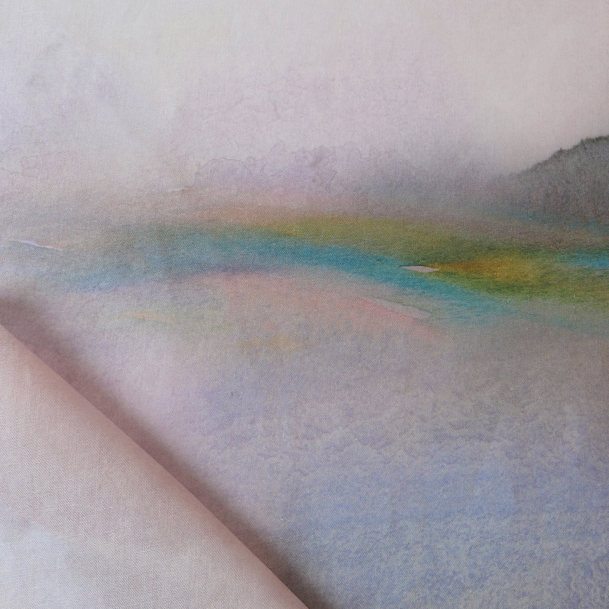 Draped fabric yardage in an ombré watercolor print in shades of pink, purple and blue on a cream field.