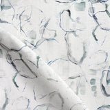 Detail of draped fabric in a watercolor painterly print in shades of gray, purple and cream.