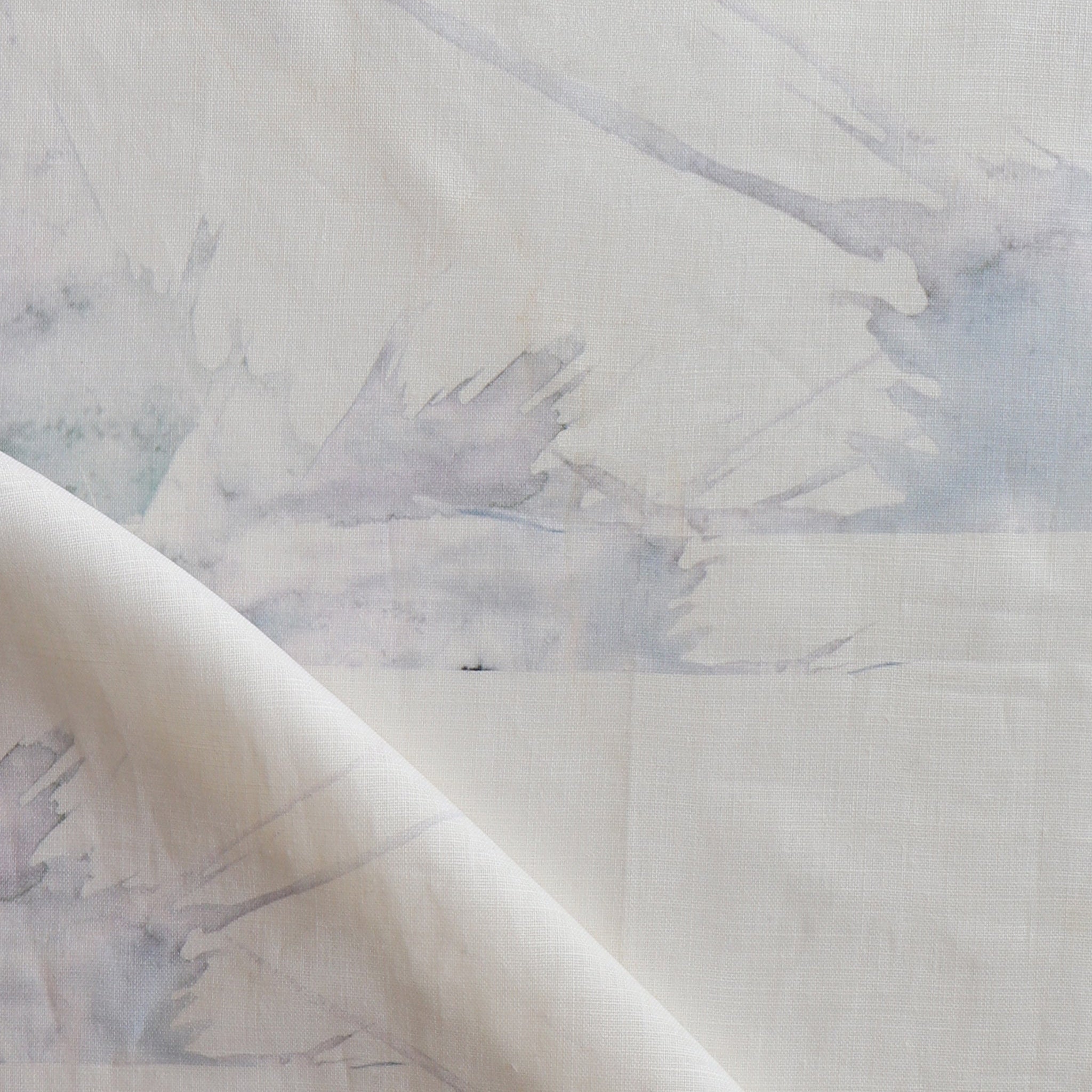Draped fabric yardage in a watercolor splatter print in pastel purple and gray on a cream field.