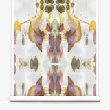 Partially unrolled wallpaper yardage in a watercolor paint blotch print in shades of gray, yellow and pink on a white field.
