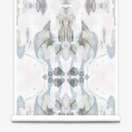 Partially unrolled wallpaper yardage in a watercolor paint blotch print in shades of gray and blue on a white field.