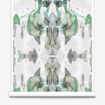 Partially unrolled wallpaper yardage in a watercolor paint blotch print in shades of gray and green on a white field.