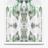 Partially unrolled wallpaper yardage in a watercolor paint blotch print in shades of gray and green on a white field.
