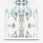 Partially unrolled wallpaper yardage in a watercolor paint blotch print in shades of gray, blue and tan on a white field.