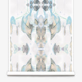 Partially unrolled wallpaper yardage in a watercolor paint blotch print in shades of gray, blue and tan on a white field.
