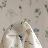 Draped fabric in a painterly flower print in front of a wall papered in the same design.