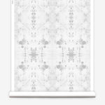 Partially unrolled wallpaper yardage in a watercolor ink blot print in gray on a white field.