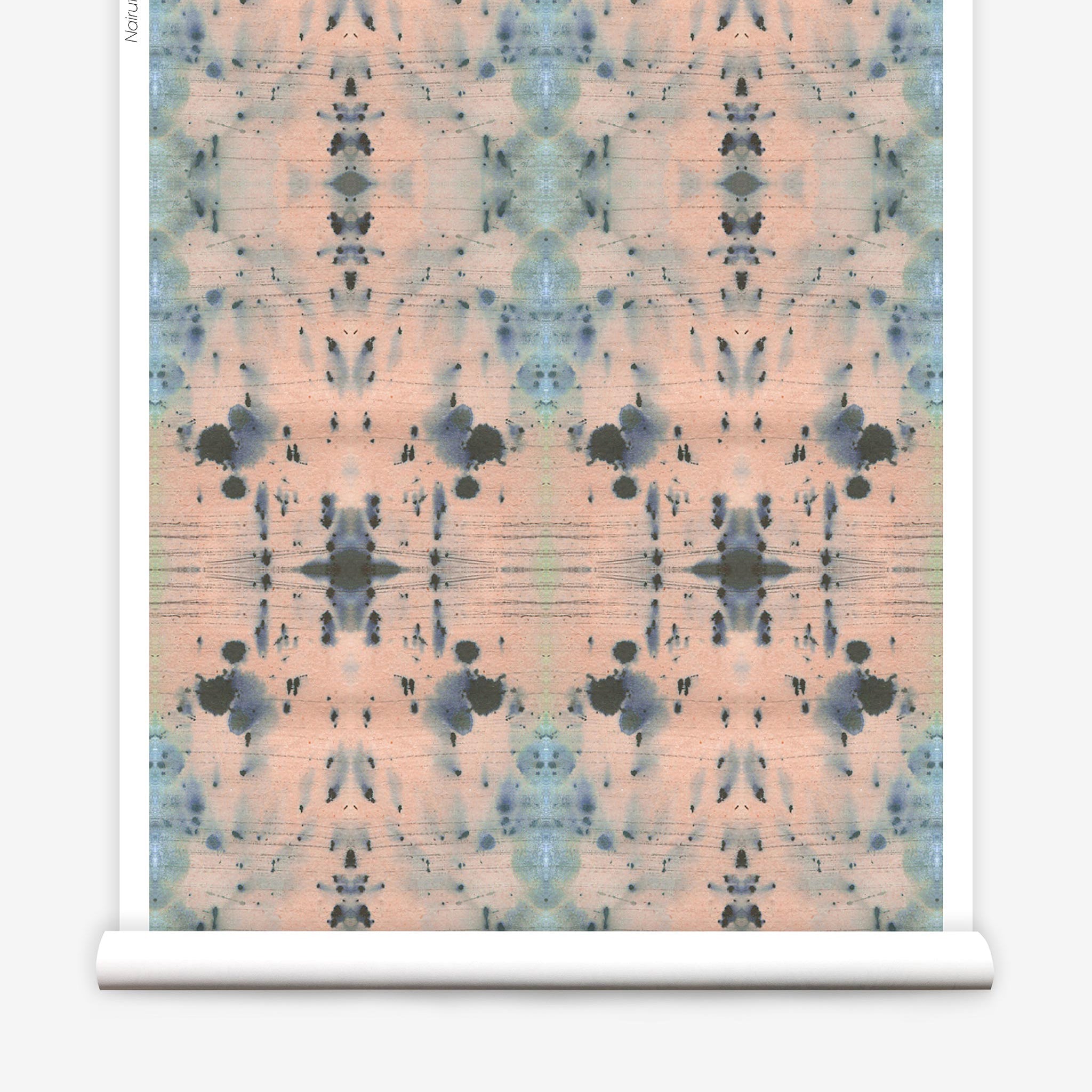 Partially unrolled wallpaper yardage in a watercolor ink blot print in blue and gray on a light pink field.