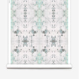 Partially unrolled wallpaper yardage in a watercolor ink blot print in gray and green on a cream field.