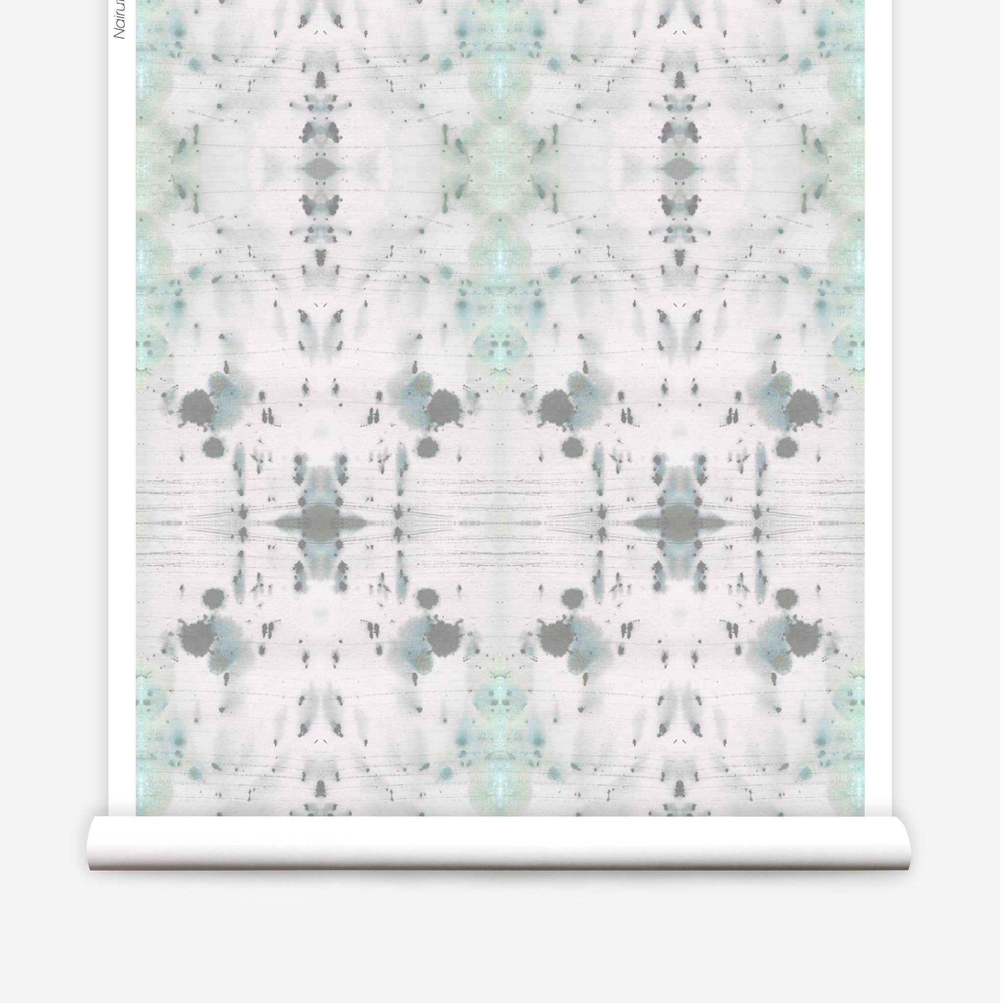 Partially unrolled wallpaper yardage in a watercolor ink blot print in gray and green on a cream field.