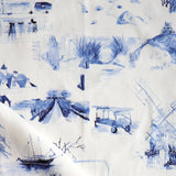 Draped fabric yardage in a playful painterly landscape print in navy on a cream field.