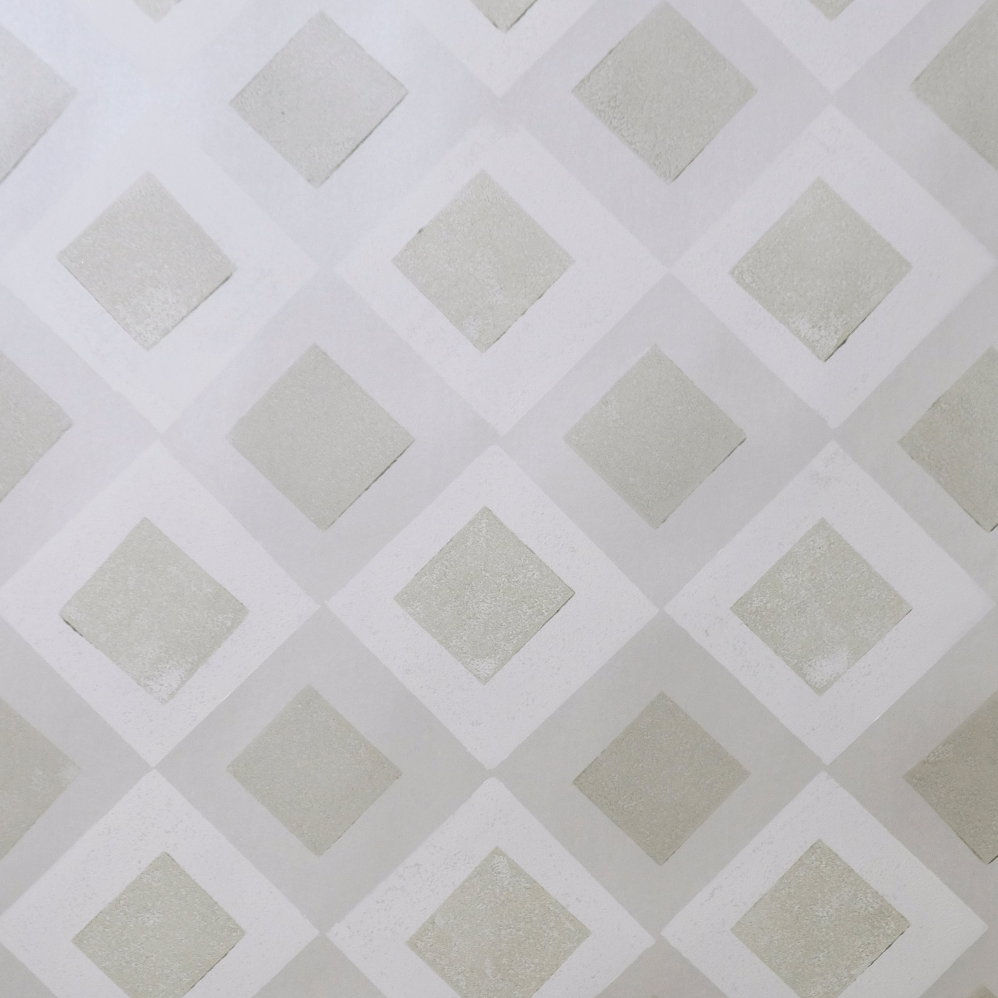 Detail of wallpaper in a diamond lattice print in shades of cream and grey.