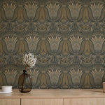 A table with a vase and cups stands in front of a wall papered in a floral damask print in cream, gold and navy.
