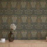 A table with a vase and cups stands in front of a wall papered in a floral damask print in cream, gold and navy.