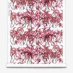 Partially unrolled wallpaper yardage in a painterly palm tree stripe print in pink, red and white.