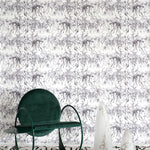 A modernist living tableau with a wall papered in a painterly palm tree stripe print in gray and white.