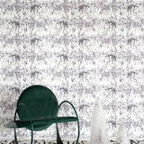 A modernist living tableau with a wall papered in a painterly palm tree stripe print in gray and white.