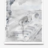 Partially unrolled wallpaper yardage in a watercolor painterly print in shades of gray and white.