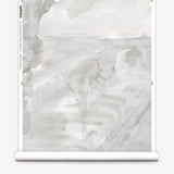 Partially unrolled wallpaper yardage in a watercolor painterly print in shades of gray and cream.