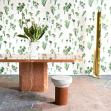 A modernist living tableau with a wall papered in a playful palm tree print in shades of green on a white field.
