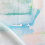 Draped fabric yardage in a watercolor watercolor print in shades of pastel and turquoise on a white field.