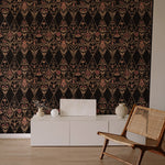 An armchair and credenza stand in front of a wall papered in a floral and diamond lattice print in pink, tan and black.