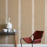 Modern interior with a red chair, table, and decorative items against a beige wall with white stripe pattern. 