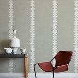 Modern interior with a red chair, table, and decorative items against a gray wall with white stripe pattern.