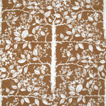 Detail of fabric in a large-scale tree and leaf print in cream on a brown field.