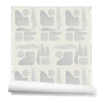 Partially unrolled wallpaper in a large-scale pattern of abstract gray watercolor shapes on a cream background.