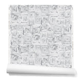 Partially unrolled wallpaper in a dense hand-drawn geometric motif in shades of gray on a white background.