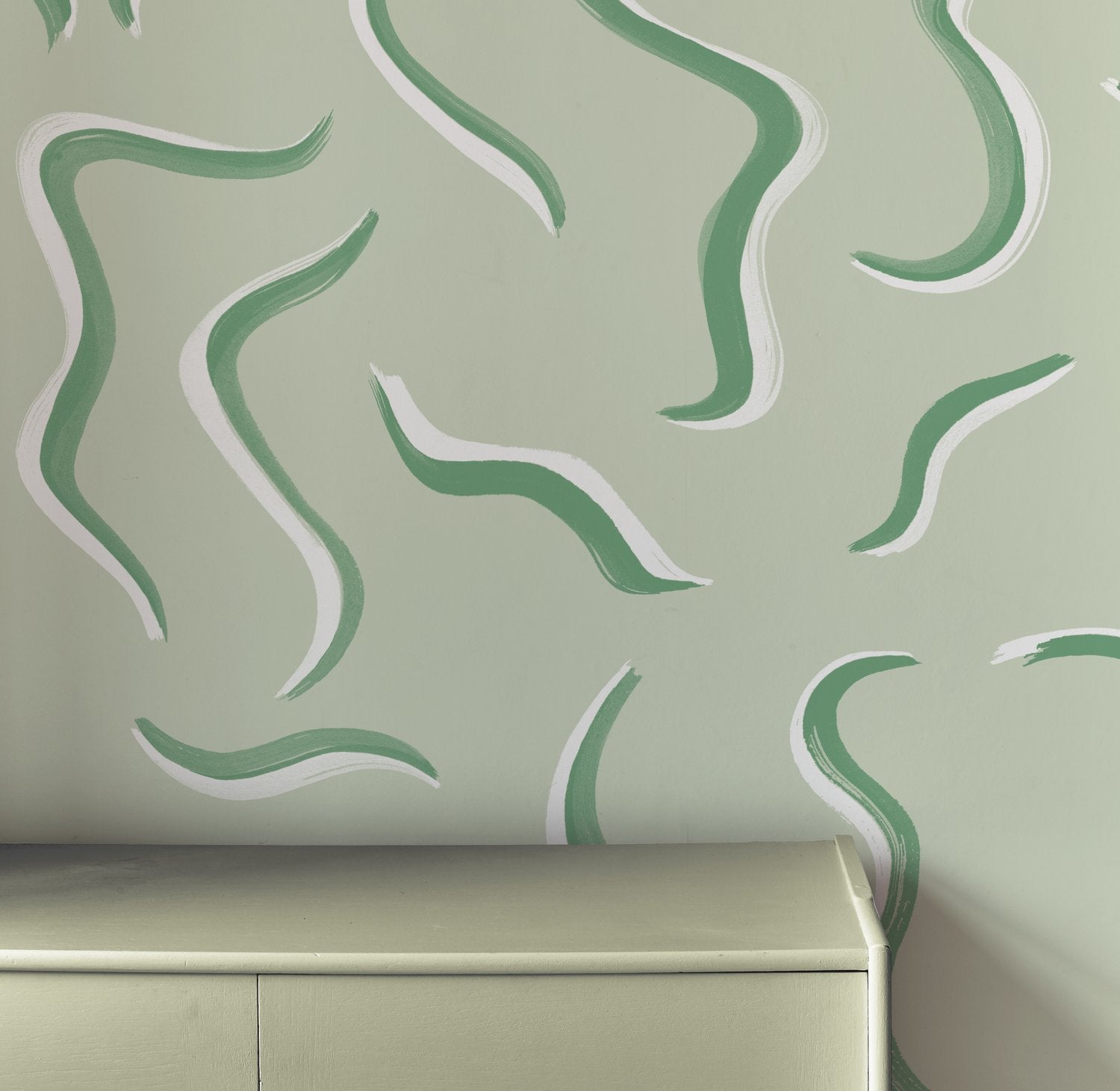An end table stands in front of a wall papered in a painterly botanical print in green and white.