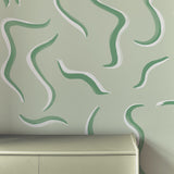 An end table stands in front of a wall papered in a painterly botanical print in green and white.